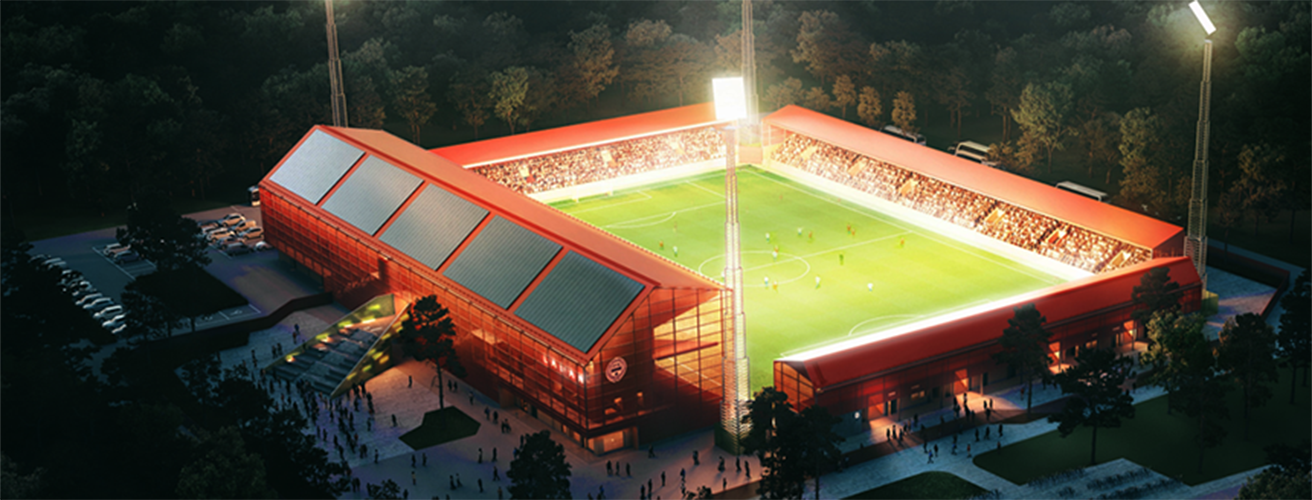 Illustration som visar den nya fotbollsarenan ovanifrån, i kvällsljus, men upplyst av starka lampor. Fotbollsplanen är omgiven av byggnader med röda träfasader och du kan se att det finns läktare runt hela arenan.