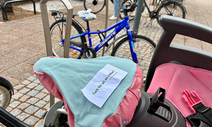 Bild som visar cykel med ett sadelskydd med texten "tack för att du cyklar"