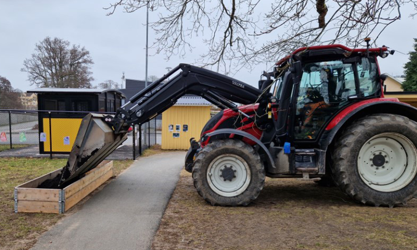 En traktor sätter en stor odlingslåda på plats.