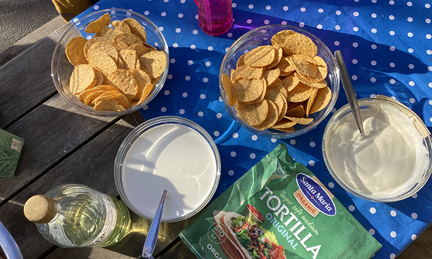 Nachos, gräddfil och grönsaker på ett fint dukat bord.