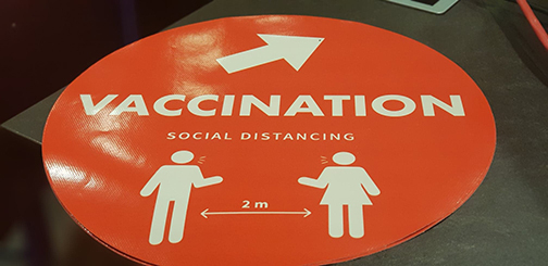 Skylt som visar texten vaccination och social distansering