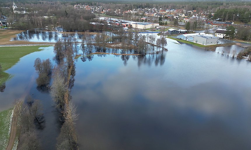 Bild från ovan som visar stora vattenmängder i förgrunden. I bakgrunden syns industribyggnader och en parkeringsplats.