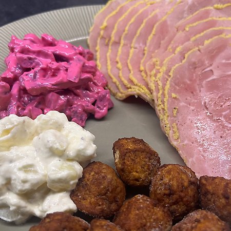 Bild på en jultallrik med rödbetssallad, potatissallad, julskinka och köttbullar på. 
