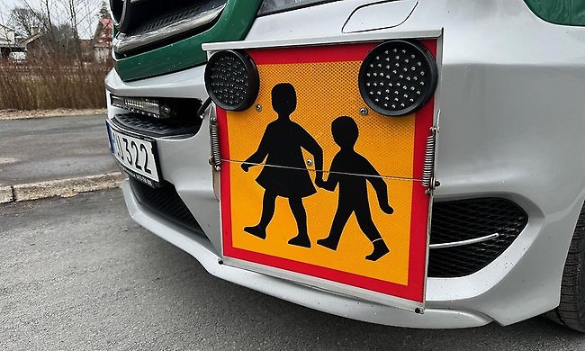 Närbild på en skolskjutsskylt sittandes på en skolbuss.